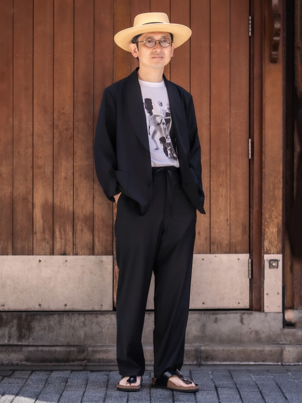 ホワイト系のTシャツ/カットソー、ブラック系のサンダル、ベージュ系のハットを着用したメンズの夏コーディネートの1枚目の写真