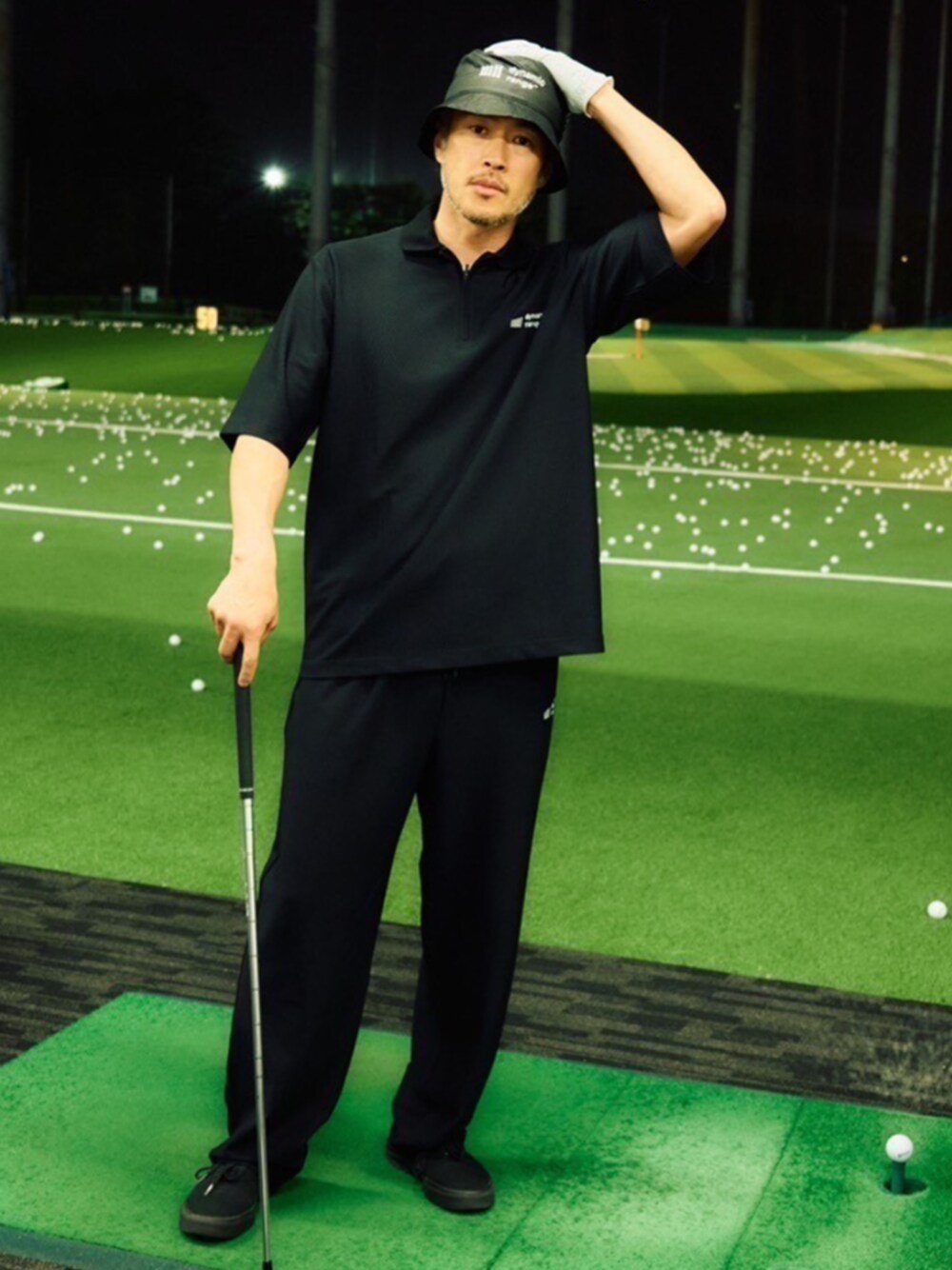 ブラック系のポロシャツ、ブラック系のスラックス、ブラック系のハットを着用したメンズの夏コーディネートの1枚目の写真