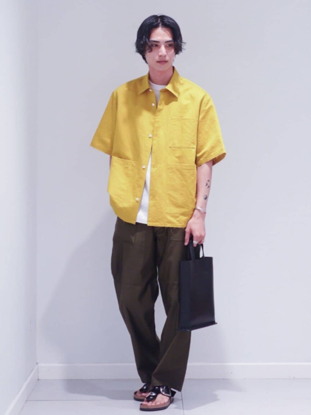 ブラック系のサンダル、イエロー系のシャツ/ブラウス、ホワイト系のTシャツ/カットソーを着用したメンズの夏コーディネートの1枚目の写真