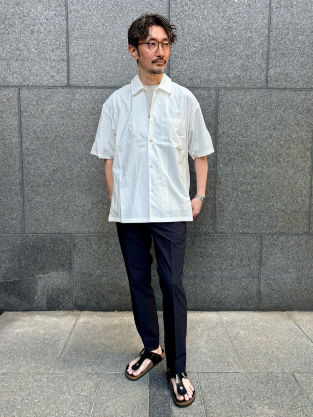 ホワイト系のシャツ/ブラウス、ブラック系のサンダル、ブルー系のスラックスを着用したメンズの夏コーディネートの1枚目の写真