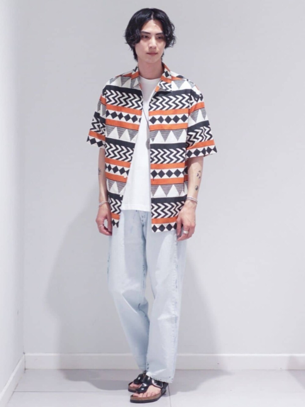 ホワイト系のデニムパンツ、ホワイト系のTシャツ/カットソー、ブラック系のサンダルを着用したメンズの夏コーディネートの1枚目の写真