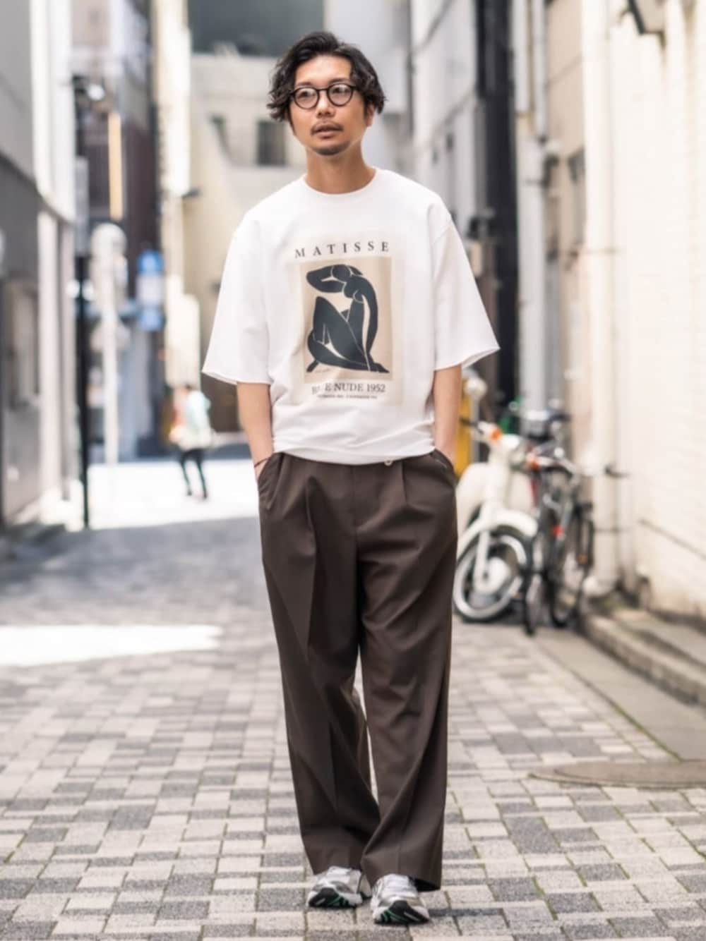 ホワイト系のTシャツ/カットソー、ブラウン系のスラックス、シルバー系のスニーカーを着用したメンズの春コーディネートの1枚目の写真