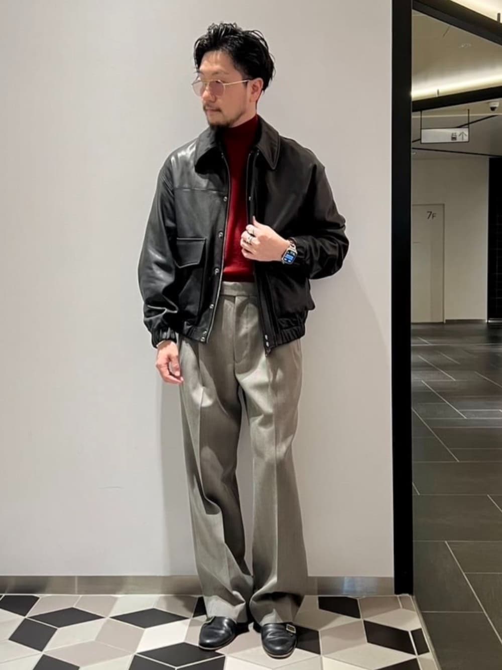 ブラック系のライダースジャケット、レッド系のニット/セーター、グレー系のスラックスを着用したメンズの秋コーディネートの1枚目の写真