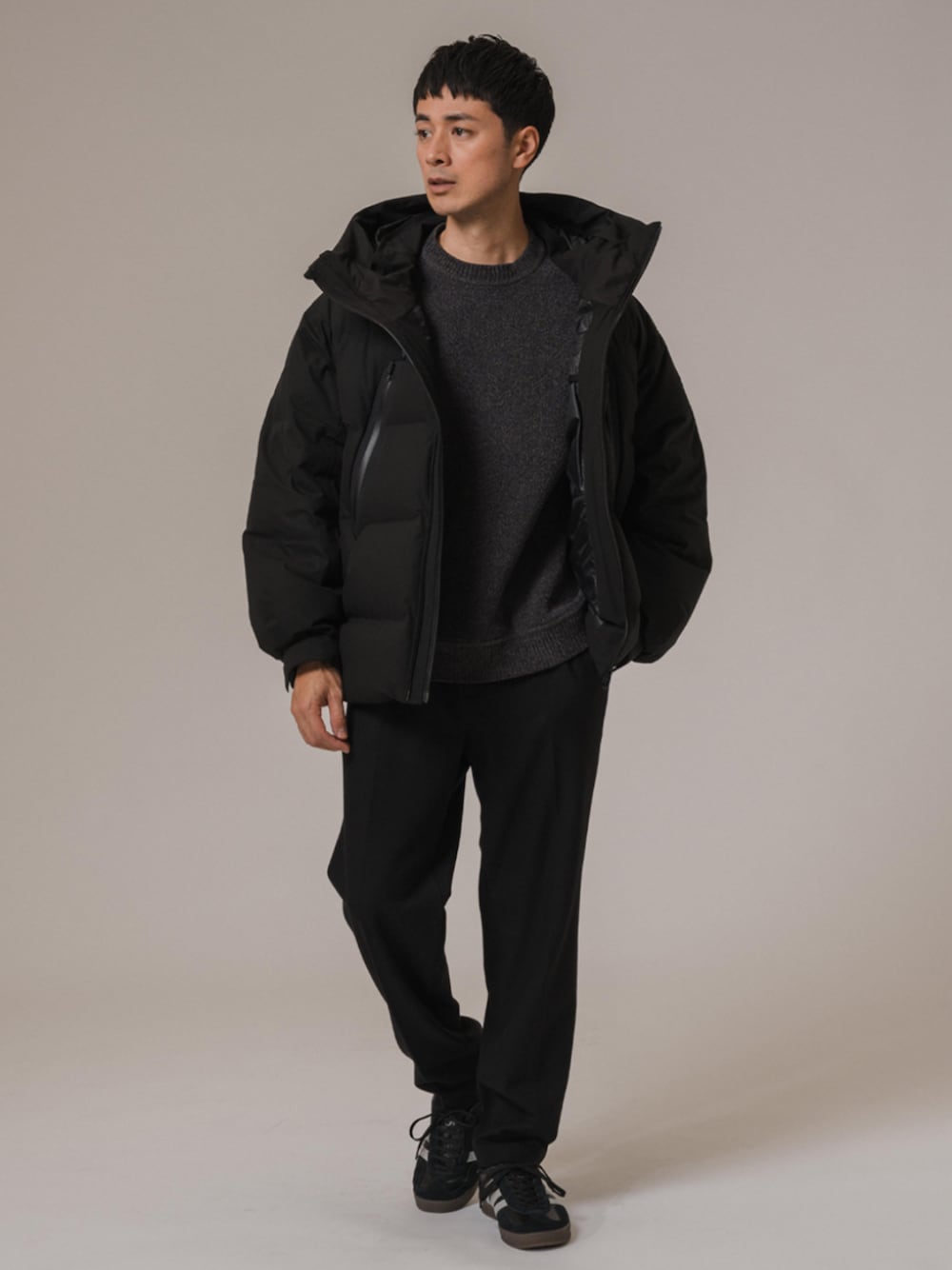 グレー系のニット/セーター、ブラック系のスラックス、ブラック系のダウンジャケット/コートを着用したメンズの冬コーディネートの1枚目の写真