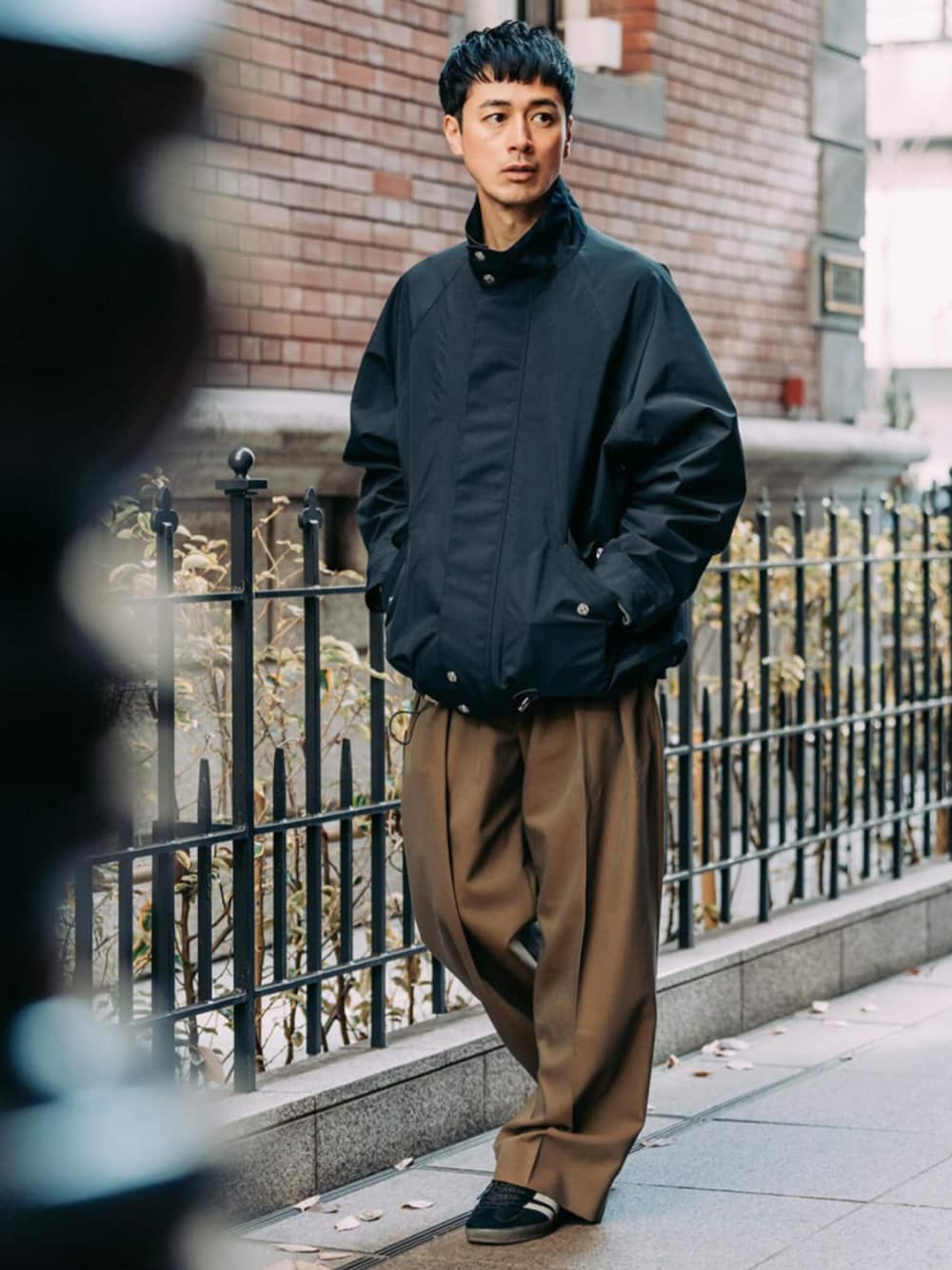 グリーン系のスラックス、ブラック系のその他アウターを着用したメンズの春コーディネートの1枚目の写真