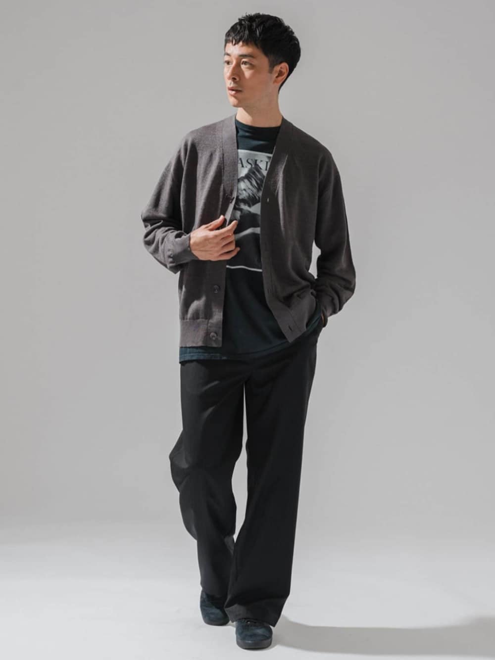 ブラック系のスラックス、グレー系のカーディガン/ボレロ、ブラック系のTシャツ/カットソーを着用したメンズの春コーディネートの1枚目の写真