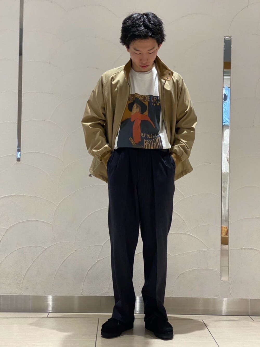 ベージュ系のブルゾン、ベージュ系のTシャツ/カットソー、ブルー系のスラックスを着用したメンズの春コーディネートの1枚目の写真