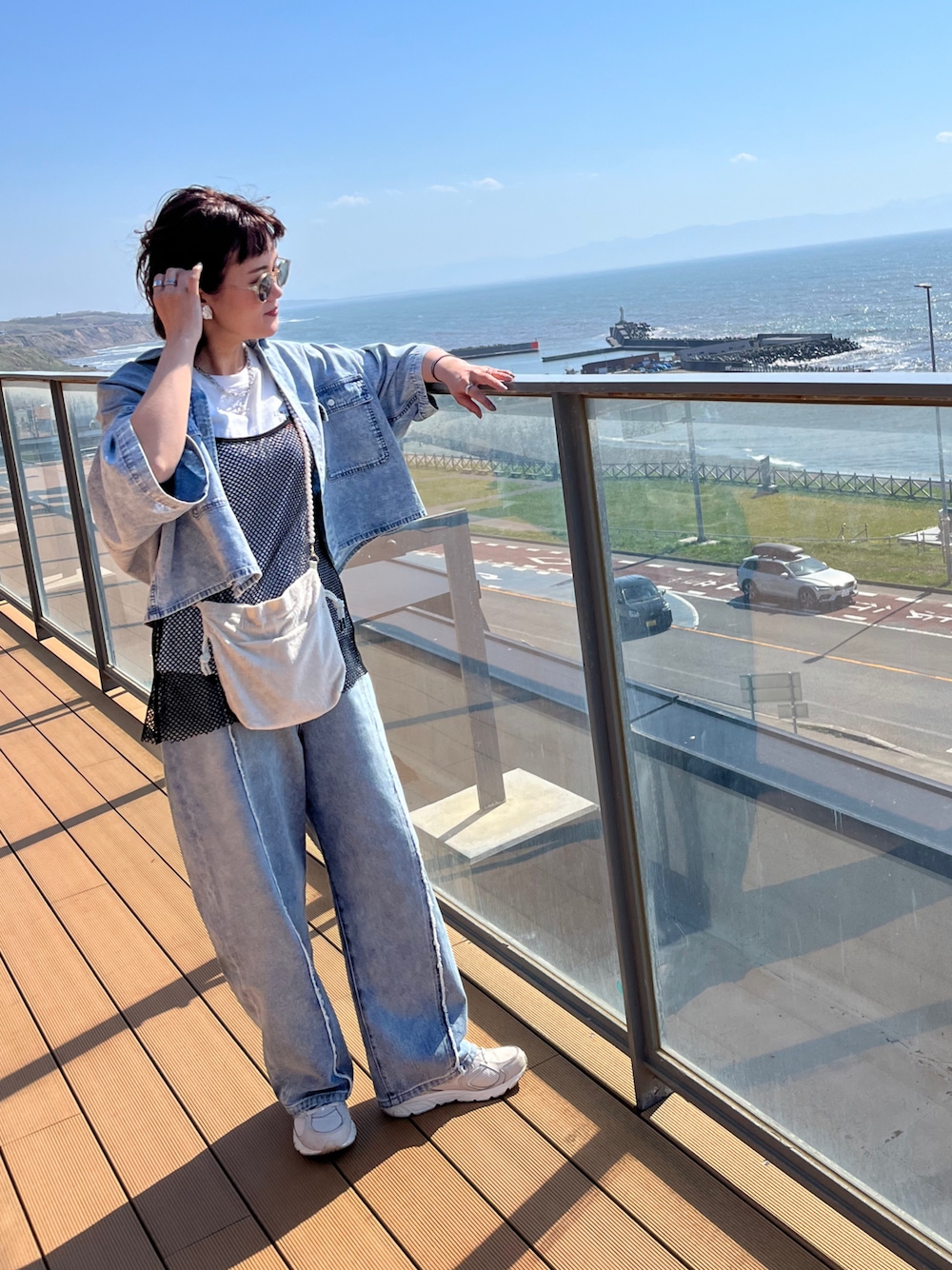 ブルー系のシャツ/ブラウス、ブルー系のデニムパンツ、ブラック系のワンピースを着用したレディースの春コーディネートの1枚目の写真