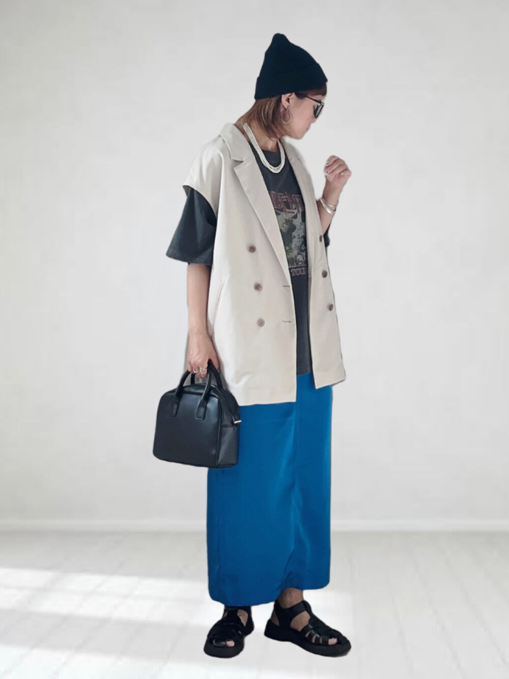 ブラック系のTシャツ/カットソー、ホワイト系のベスト、ブルー系のスカートを着用したレディースの夏コーディネートの1枚目の写真