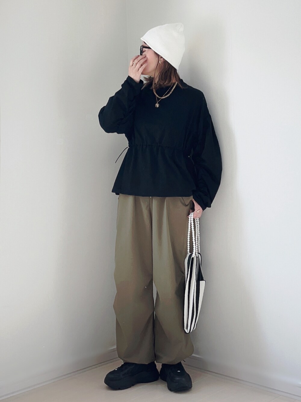 ブラック系のTシャツ/カットソー、グリーン系のその他パンツ、ホワイト系のショルダーバッグを着用したレディースの春コーディネートの1枚目の写真