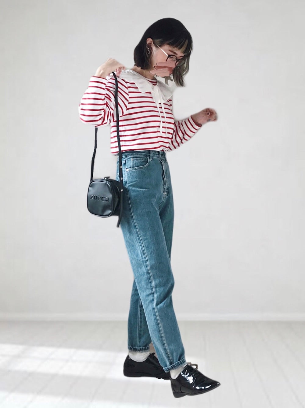 ブルー系のデニムパンツ、ホワイト系のTシャツ/カットソー、ブラック系のショルダーバッグを着用したレディースの春コーディネートの1枚目の写真