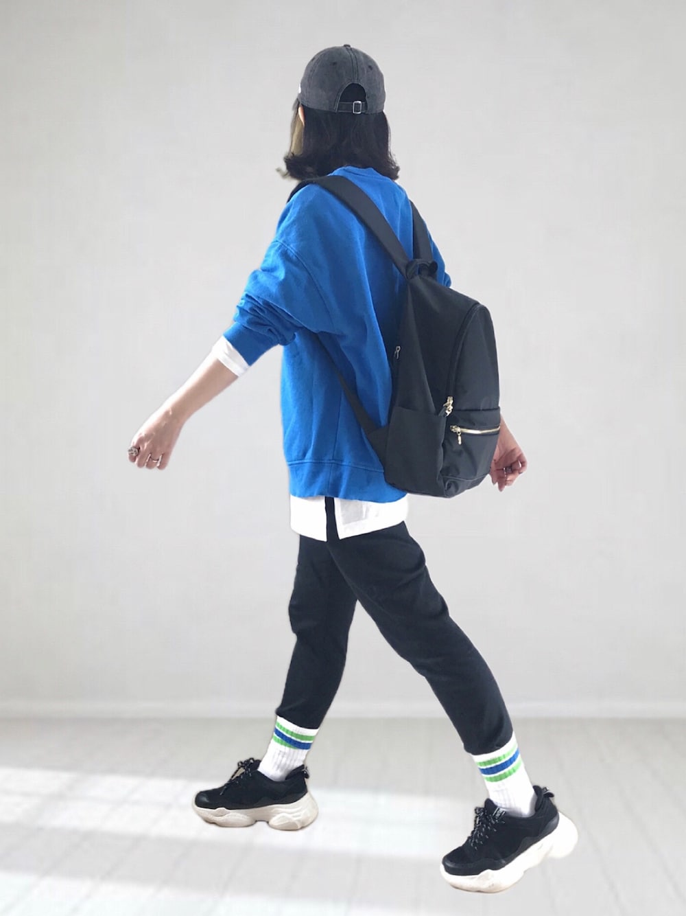 ブラック系のデニムパンツ、ブルー系のスウェット、ブラック系のバックパック/リュックを着用したレディースの春コーディネートの1枚目の写真