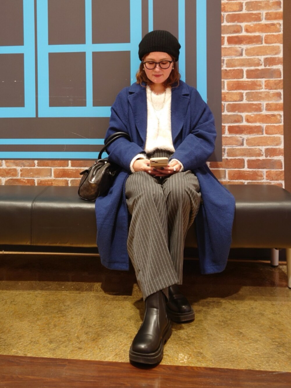 ホワイト系のニット/セーター、ブルー系のチェスターコート、グレー系のその他パンツを着用したレディースの冬コーディネートの1枚目の写真