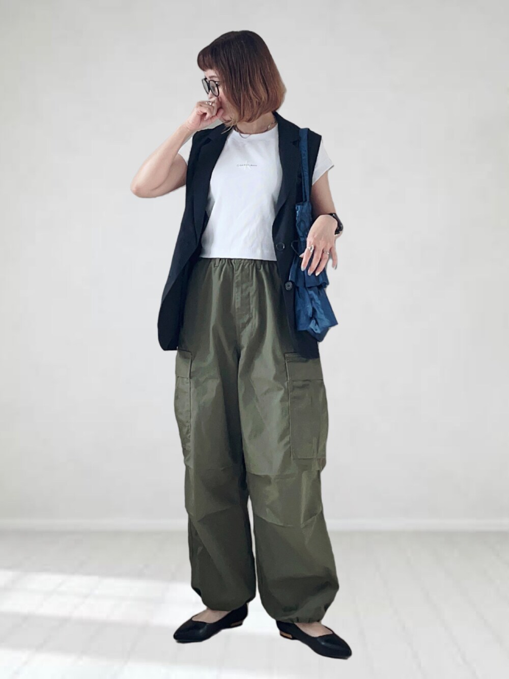 ホワイト系のTシャツ/カットソー、ブラック系のベスト、グリーン系のカーゴパンツを着用したレディースの春コーディネートの1枚目の写真