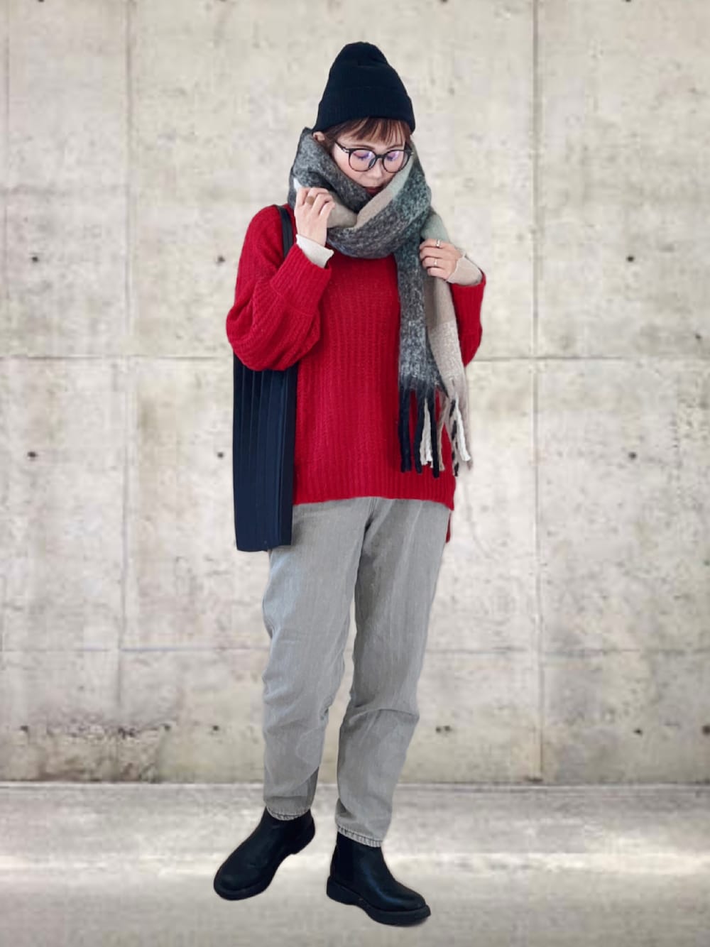 レッド系のニット/セーター、ベージュ系のデニムパンツ、ブラック系のトートバッグを着用したレディースの冬コーディネートの1枚目の写真