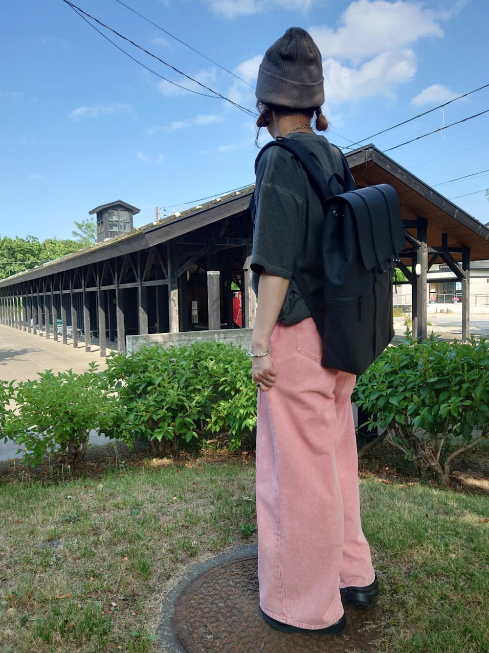 ブラック系のバックパック/リュック、グレー系のTシャツ/カットソー、ブラック系のサンダルを着用したレディースの夏コーディネートの1枚目の写真