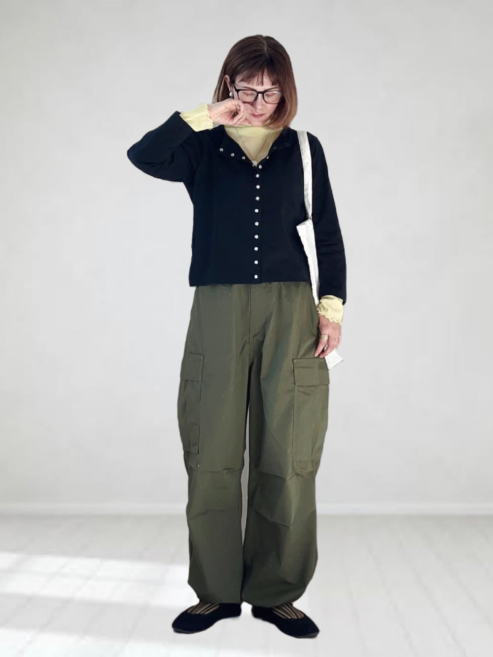 ブラック系のカーディガン/ボレロ、イエロー系のTシャツ/カットソー、グリーン系のカーゴパンツを着用したレディースの春コーディネートの1枚目の写真