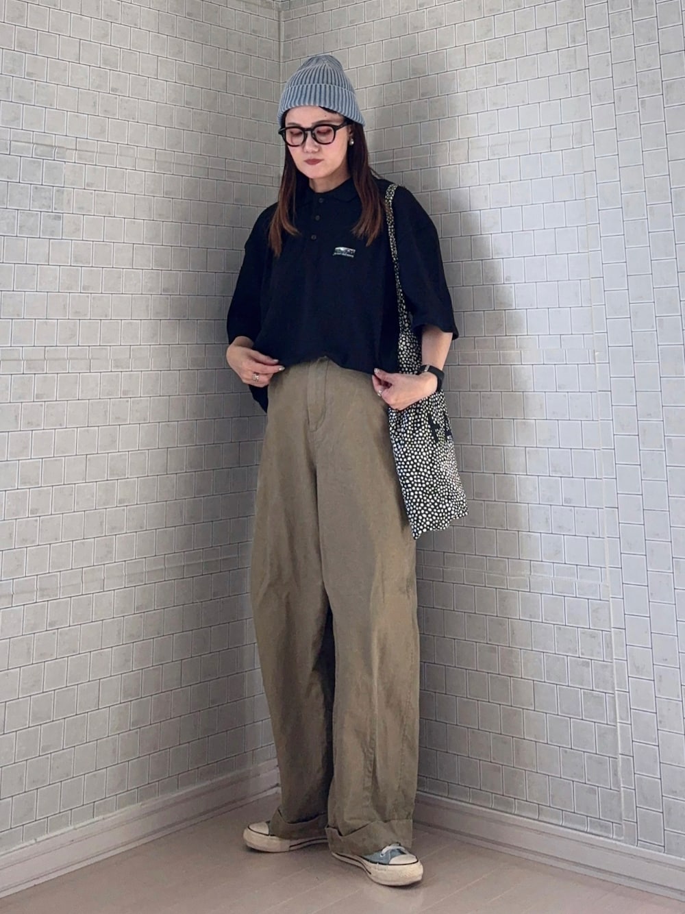 ベージュ系のその他パンツ、ブラック系のポロシャツ、ブラック系のトートバッグを着用したレディースの春コーディネートの1枚目の写真