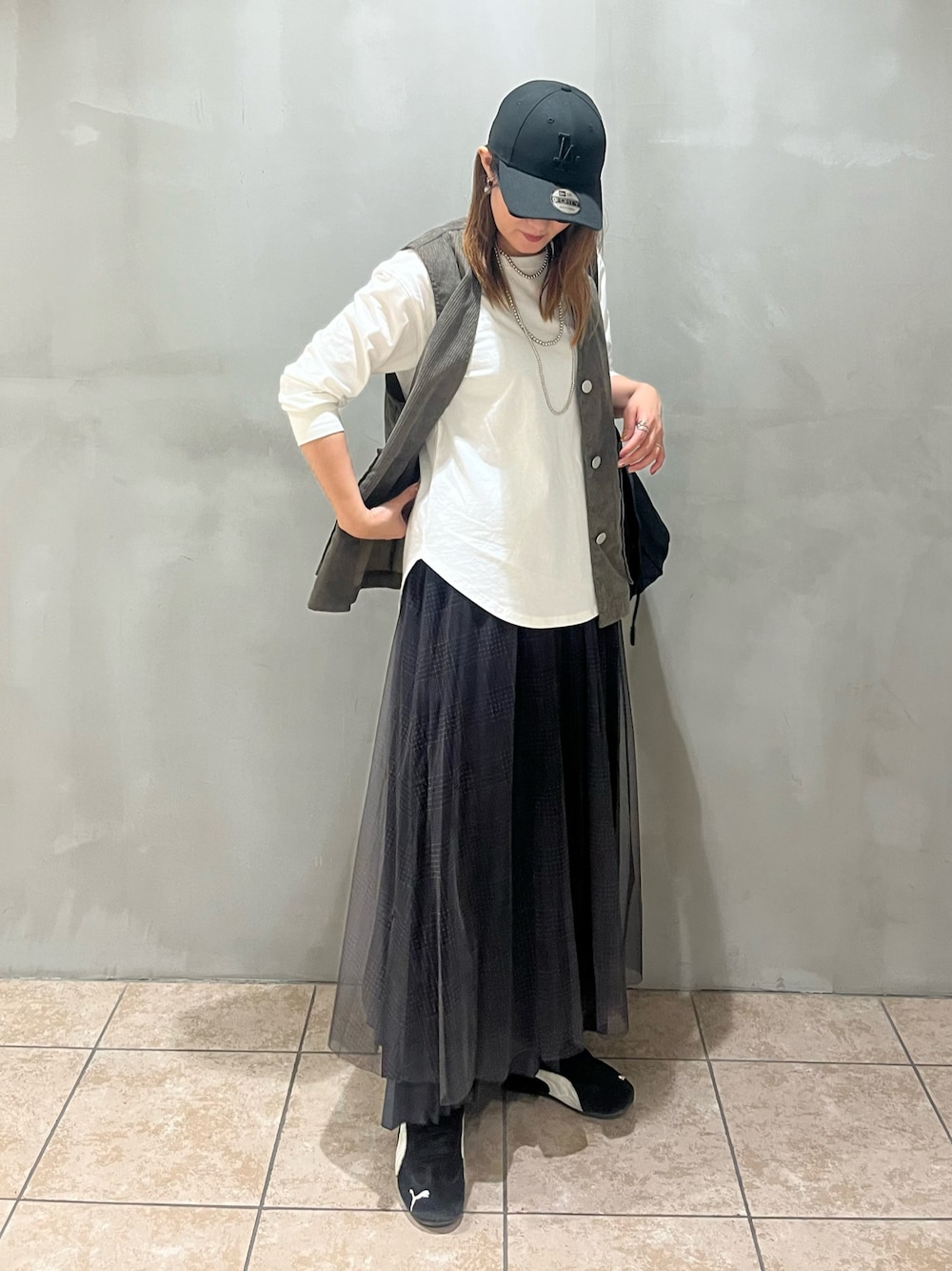 ホワイト系のTシャツ/カットソー、グレー系のスカート、グリーン系のベストを着用したレディースの秋コーディネートの1枚目の写真