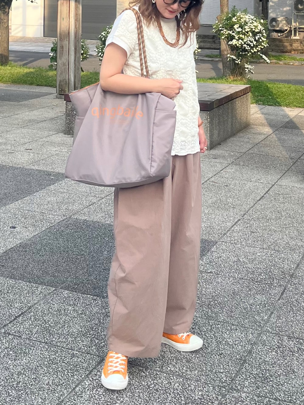 グレー系のトートバッグ、ホワイト系のTシャツ/カットソー、オレンジ系のスニーカーを着用したレディースの夏コーディネートの1枚目の写真