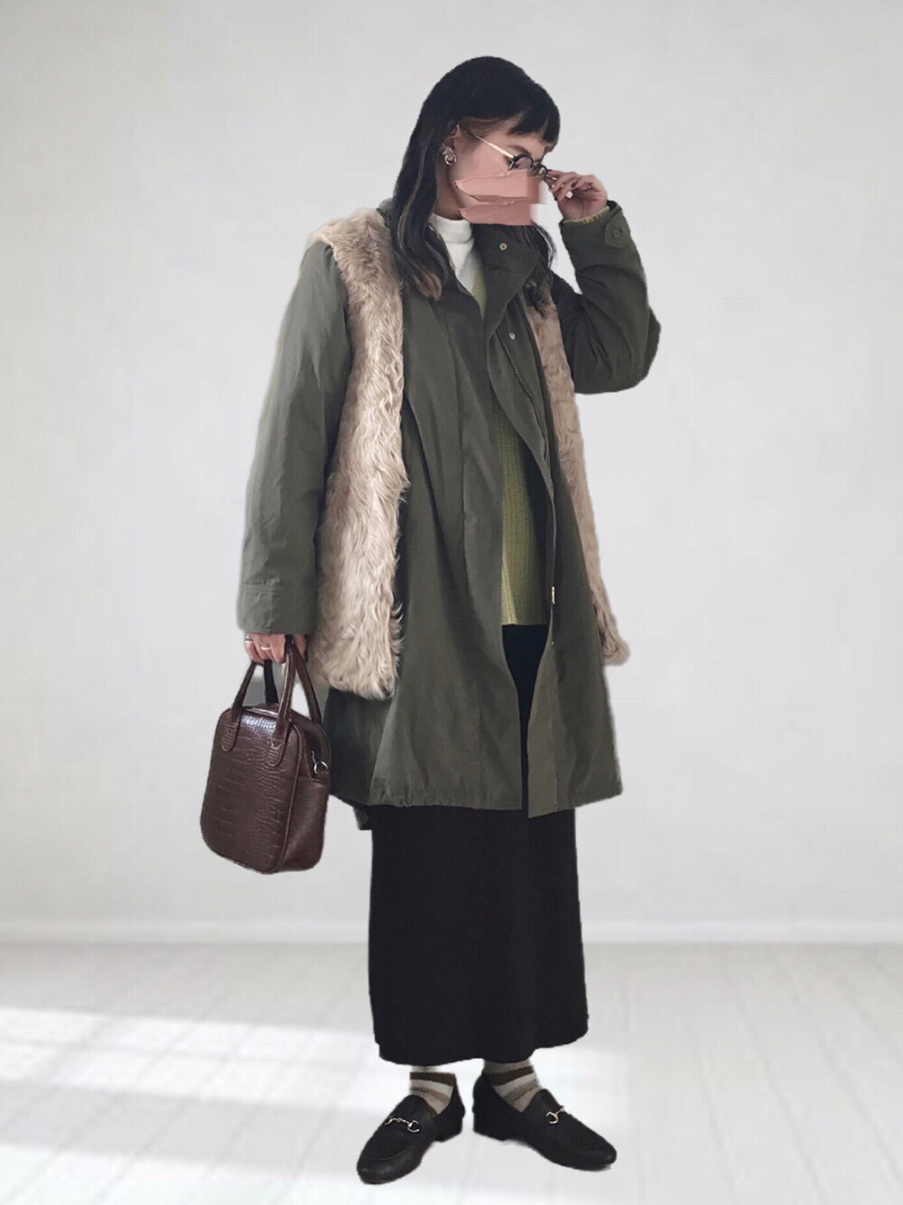 ベージュ系のベスト、グリーン系のモッズコート、ホワイト系のTシャツ/カットソーを着用したレディースの冬コーディネートの1枚目の写真