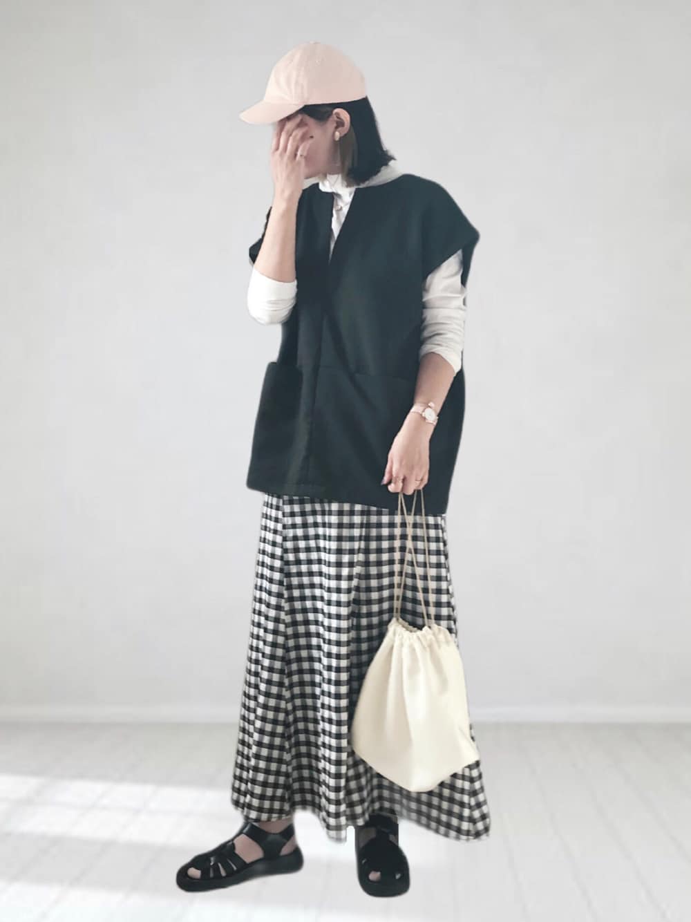 ブラック系のスカート、ホワイト系のTシャツ/カットソー、ブラック系のベストを着用したレディースの春コーディネートの1枚目の写真