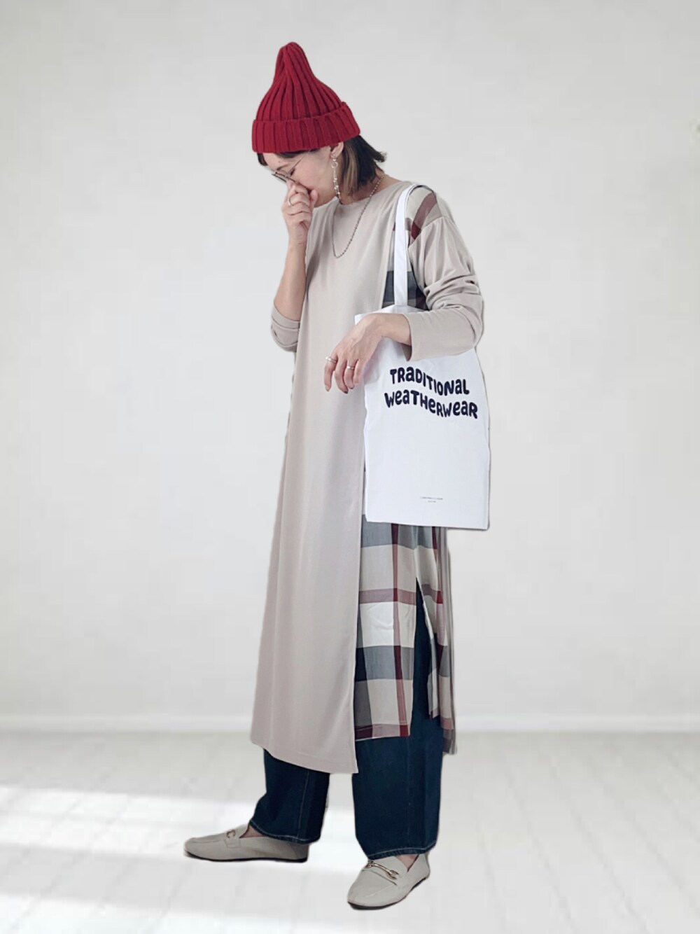 ベージュ系のワンピース、ブルー系のデニムパンツ、ホワイト系のトートバッグを着用したレディースの秋コーディネートの1枚目の写真