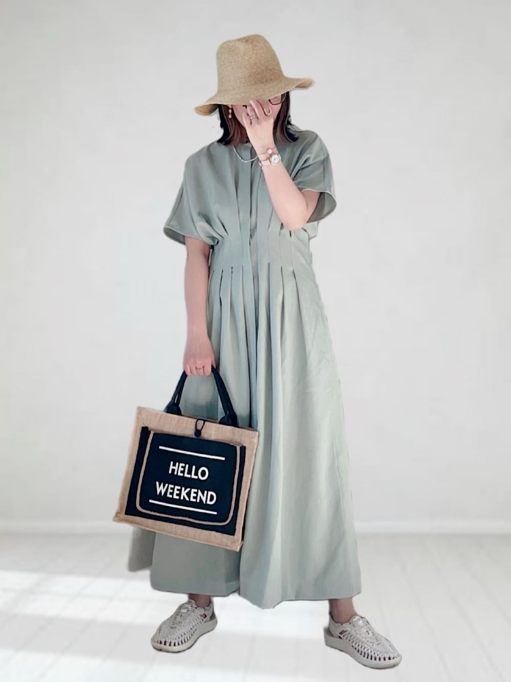 グリーン系のワンピース、ブラック系のかごバッグ、ホワイト系のサンダルを着用したレディースの春コーディネートの1枚目の写真
