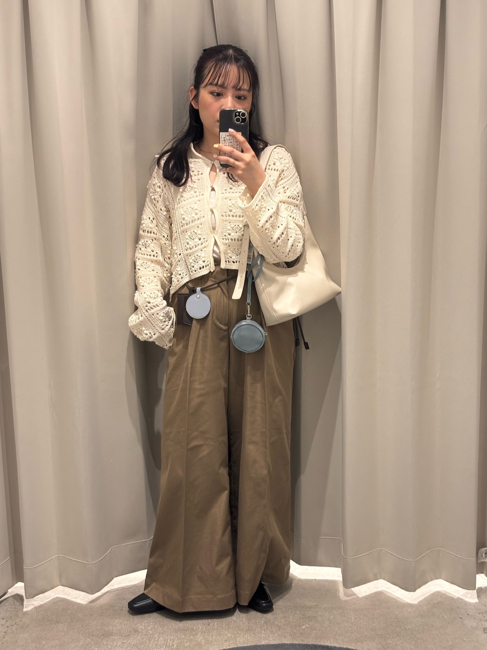 ホワイト系のカーディガン/ボレロ、ホワイト系のキャミソール、ベージュ系のハンドバッグを着用したレディースの春コーディネートの1枚目の写真