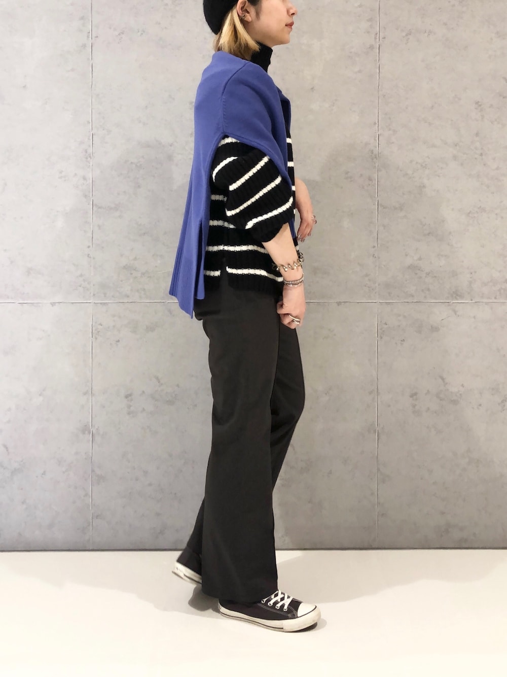 グレー系のチノパンツ、グレー系のスニーカー、ブラック系のニット/セーターを着用したレディースの冬コーディネートの2枚目の写真