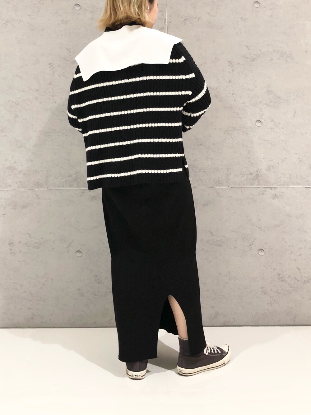 ブラック系のスカート、グレー系のスニーカー、ブラック系のニット/セーターを着用したレディースの冬コーディネートの3枚目の写真