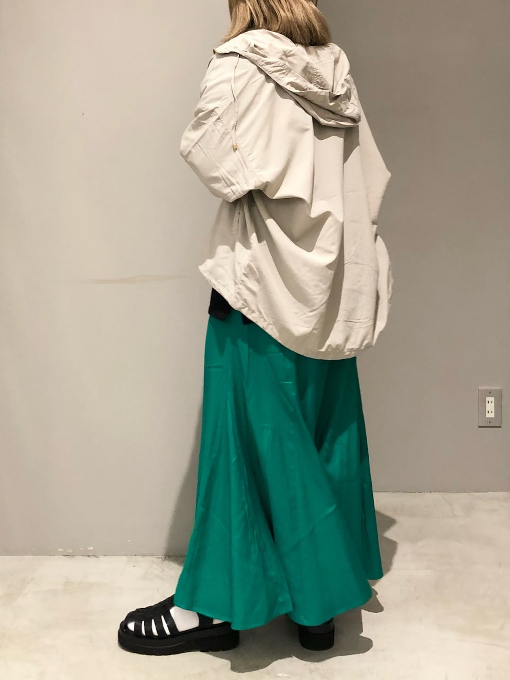 グリーン系のスカート、ブラック系のTシャツ/カットソー、ブラック系のサンダルを着用したレディースの春コーディネートの2枚目の写真