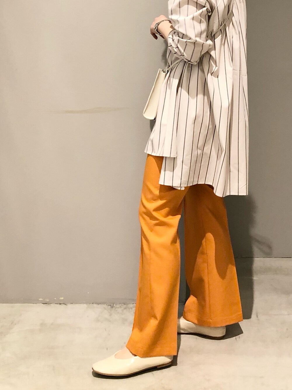 ベージュ系のシャツ/ブラウス、オレンジ系のその他パンツ、ホワイト系のパンプスを着用したレディースの春コーディネートの3枚目の写真