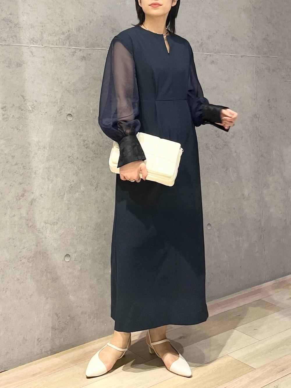 ホワイト系のショルダーバッグ、ホワイト系のパンプス、ブルー系のドレスを着用したレディースの夏コーディネートの1枚目の写真