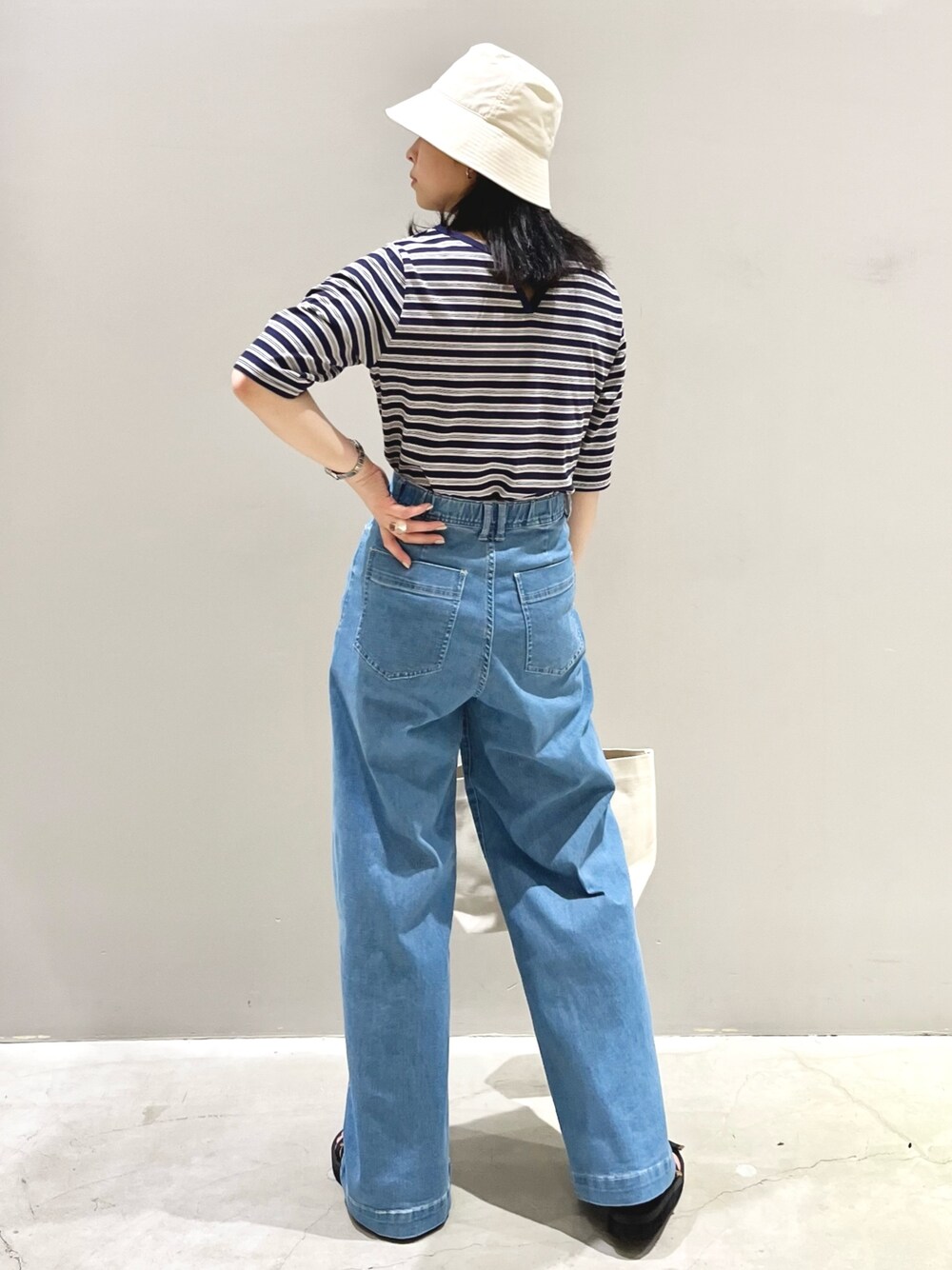 ブルー系のTシャツ/カットソー、ブルー系のデニムパンツ、ホワイト系のトートバッグを着用したレディースの夏コーディネートの2枚目の写真