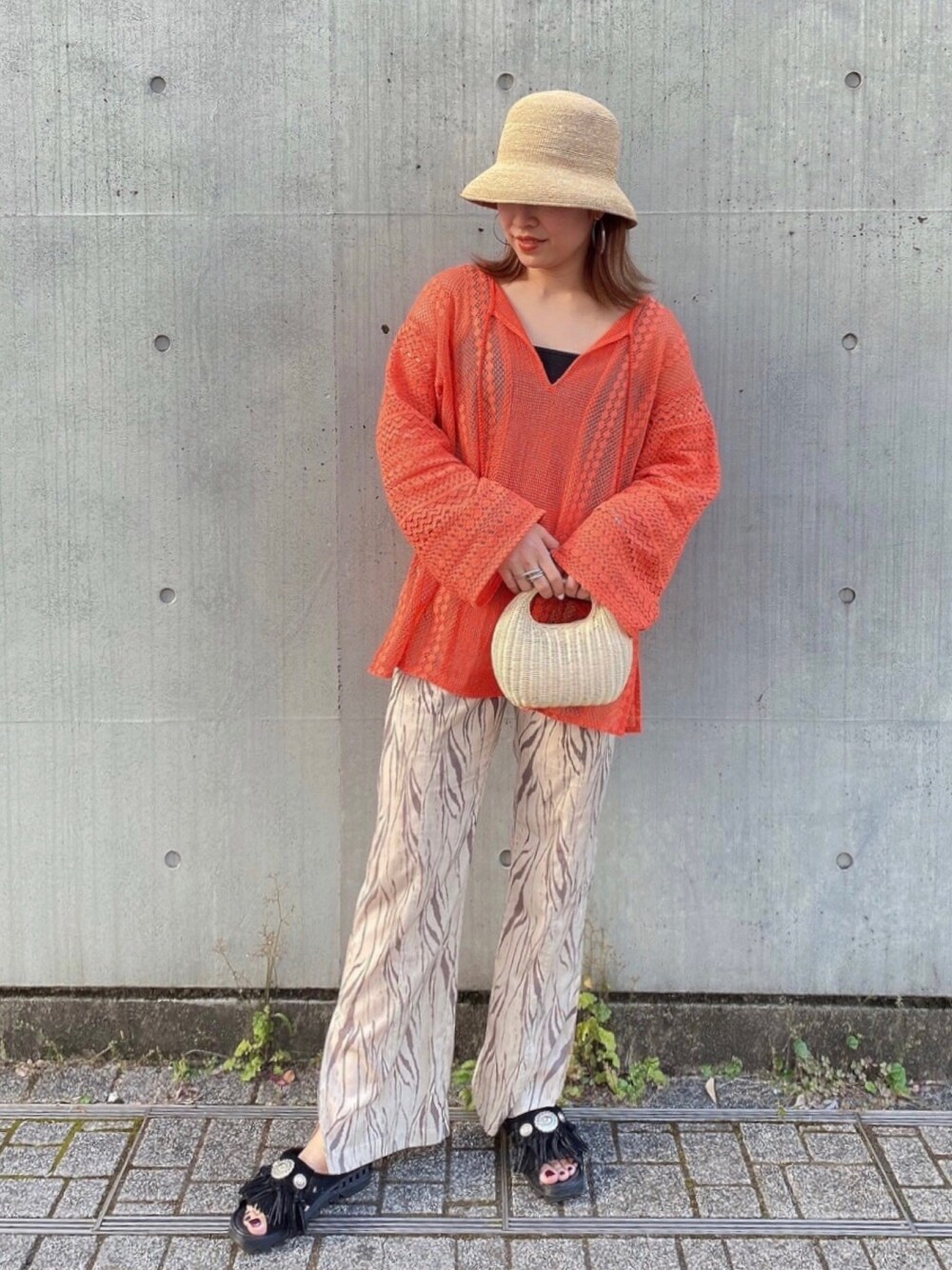 ブラック系のサンダル、ベージュ系のかごバッグ、オレンジ系のTシャツ/カットソーを着用したレディースの夏コーディネートの1枚目の写真