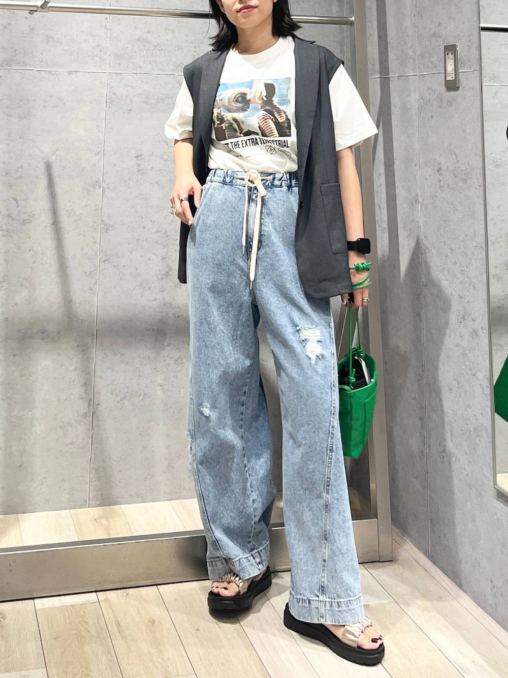 ベージュ系のサンダル、ブルー系のデニムパンツ、グリーン系のショルダーバッグを着用したレディースの夏コーディネートの1枚目の写真