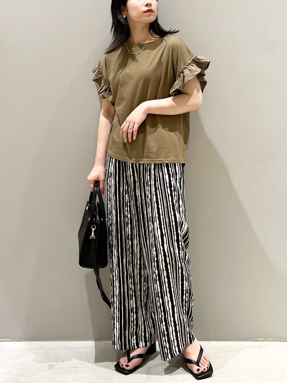 グリーン系のTシャツ/カットソー、ブラック系のサンダル、ブラック系のショルダーバッグを着用したレディースの夏コーディネートの2枚目の写真