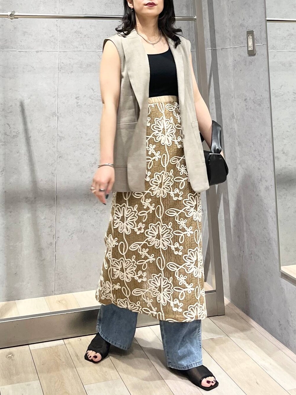 ブルー系のデニムパンツ、ブラック系のハンドバッグ、ブラック系のサンダルを着用したレディースの春コーディネートの1枚目の写真