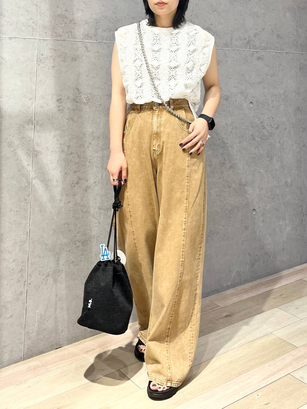 ブラック系のショルダーバッグ、ブラウン系のデニムパンツ、ブラック系のサンダルを着用したレディースの夏コーディネートの1枚目の写真