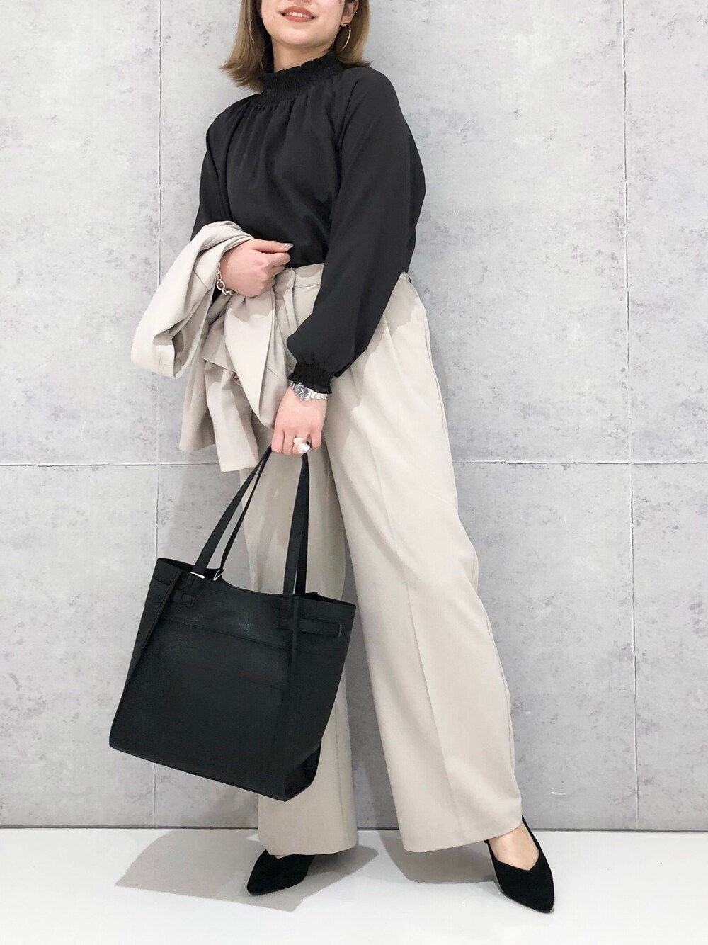 ブラック系のトートバッグ、ブラック系のパンプス、ベージュ系のスラックスを着用したレディースの冬コーディネートの2枚目の写真