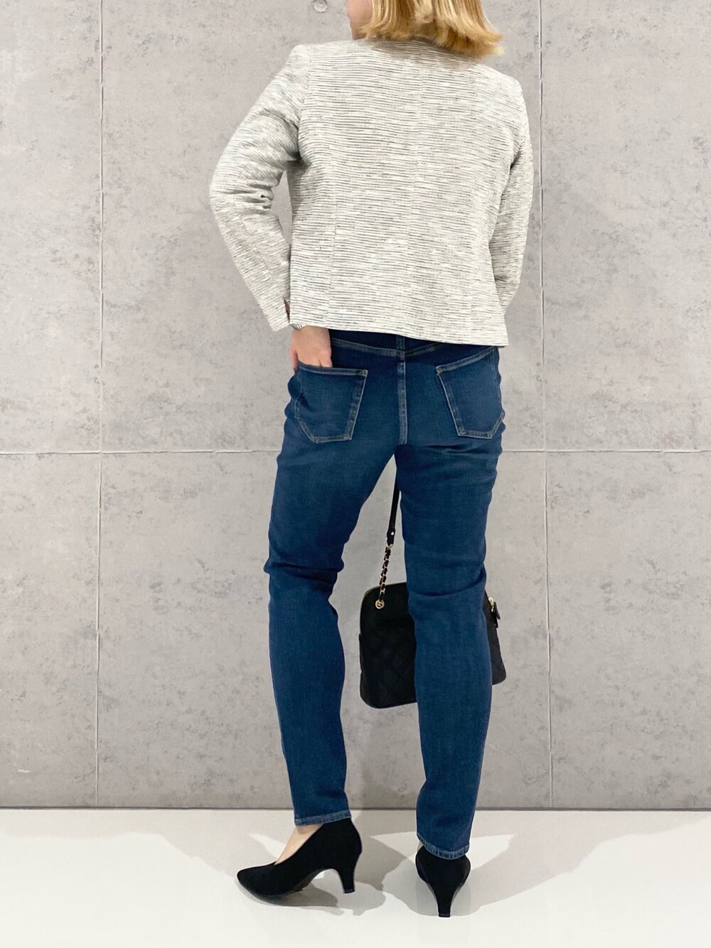 ブラック系のジャケット/アウター、ブルー系のデニムパンツ、ブラック系のショルダーバッグを着用したレディースの冬コーディネートの2枚目の写真