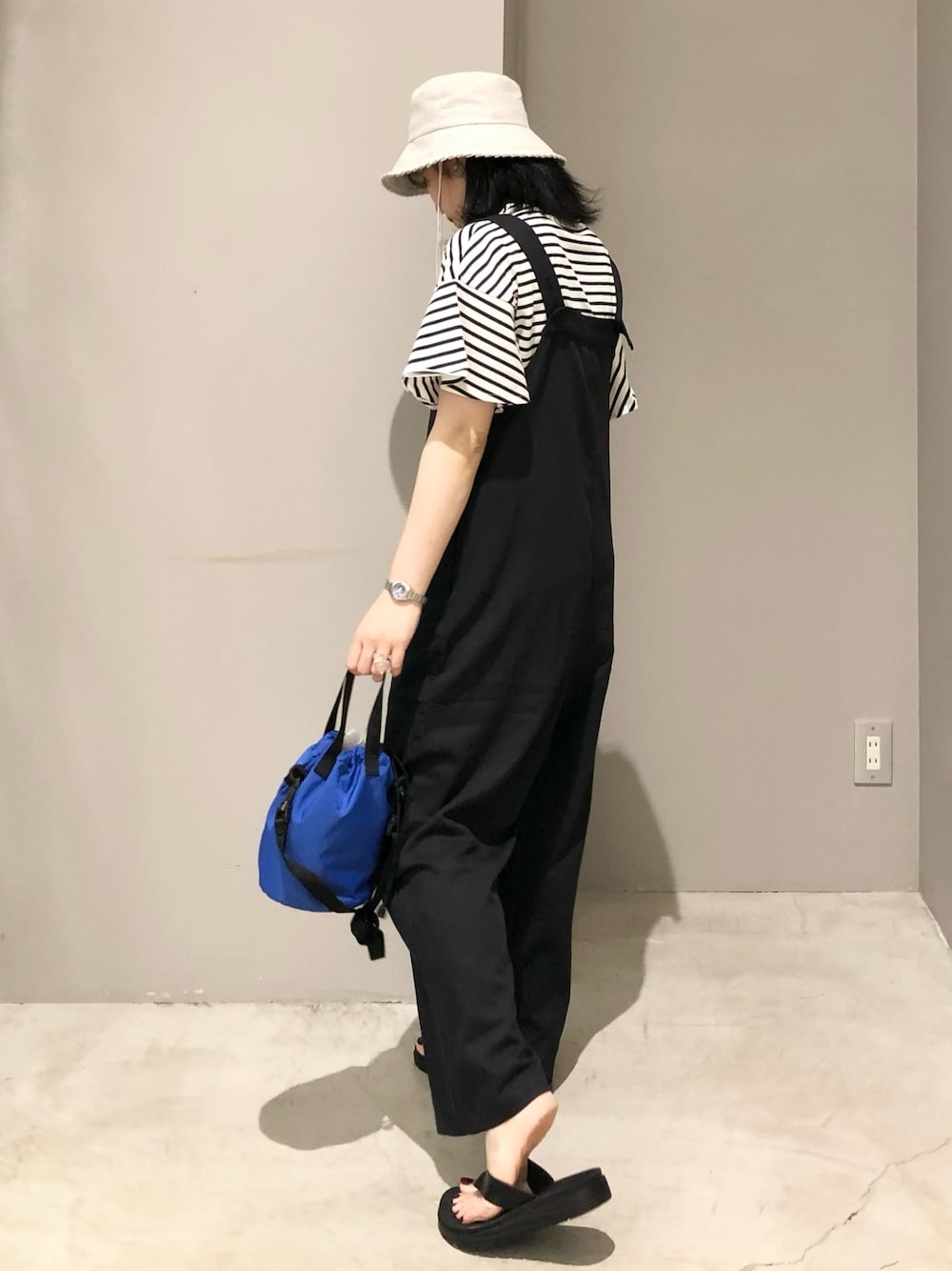 ブラック系のサロペット/オーバーオール、ブラック系のサンダル、ブルー系のショルダーバッグを着用したレディースの夏コーディネートの2枚目の写真