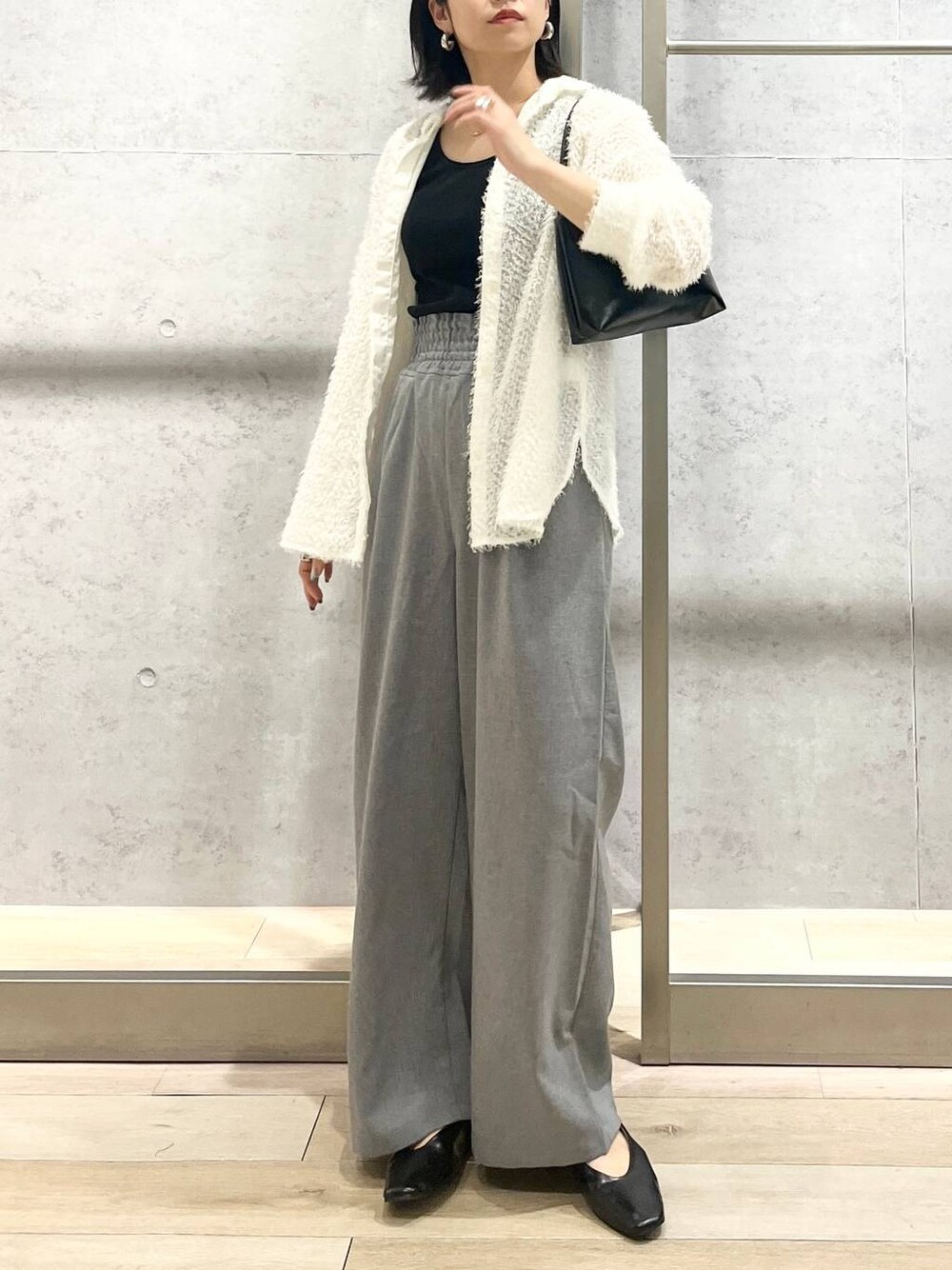 ブラック系のハンドバッグ、ホワイト系のシャツ/ブラウス、ブラック系のパンプスを着用したレディースの春コーディネートの1枚目の写真