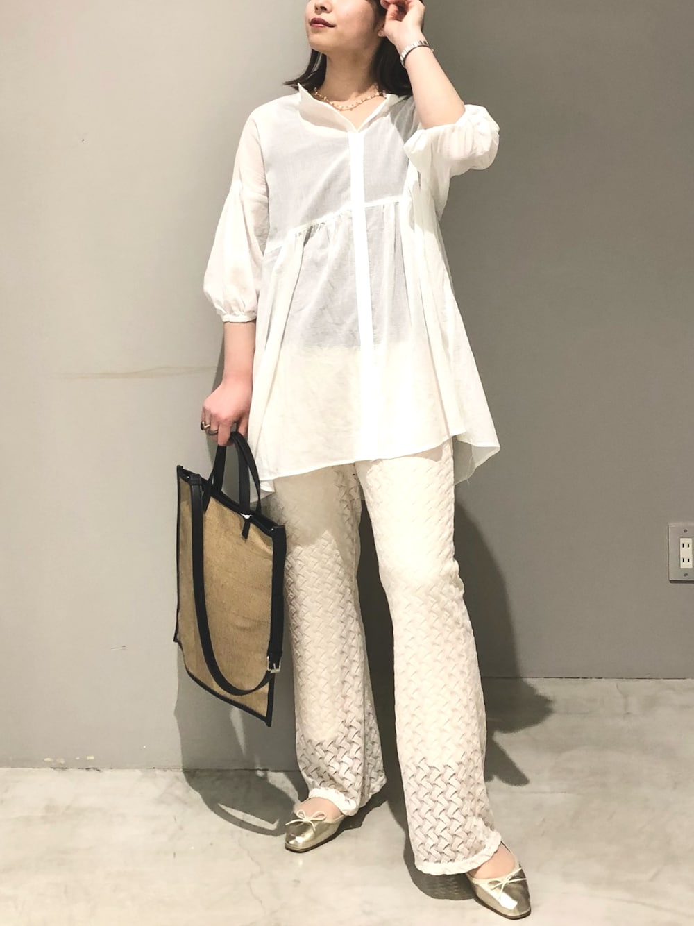 ホワイト系のその他パンツ、ゴールド系のバレエシューズ、ベージュ系のショルダーバッグを着用したレディースの春コーディネートの2枚目の写真