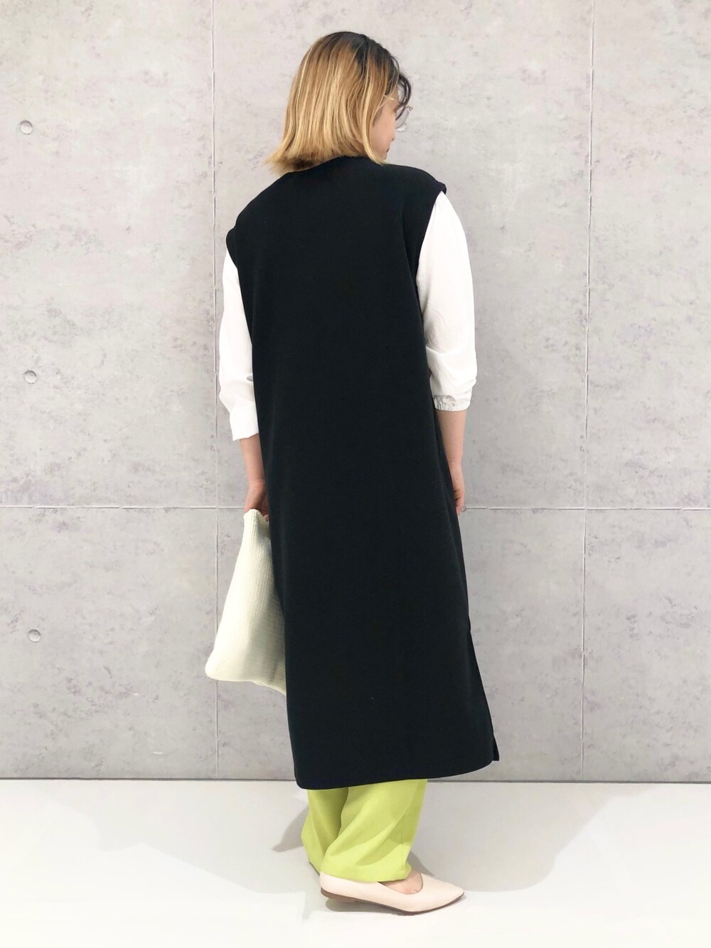 ブラック系のワンピース/ドレス、イエロー系のスラックス、ホワイト系のパンプスを着用したレディースの冬コーディネートの3枚目の写真