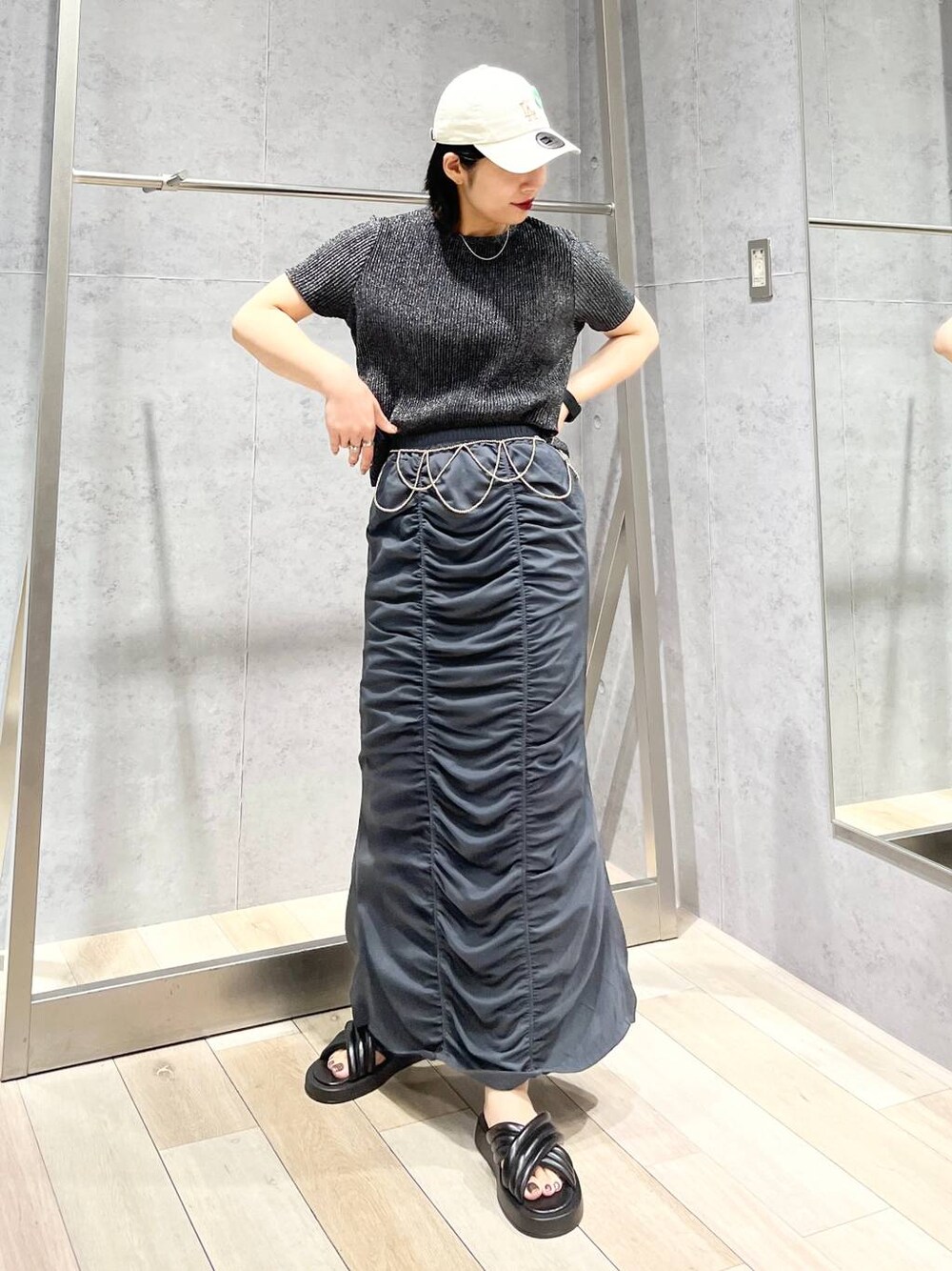 グレー系のスカート、ブラック系のサンダル、ブラック系のTシャツ/カットソーを着用したレディースの夏コーディネートの1枚目の写真