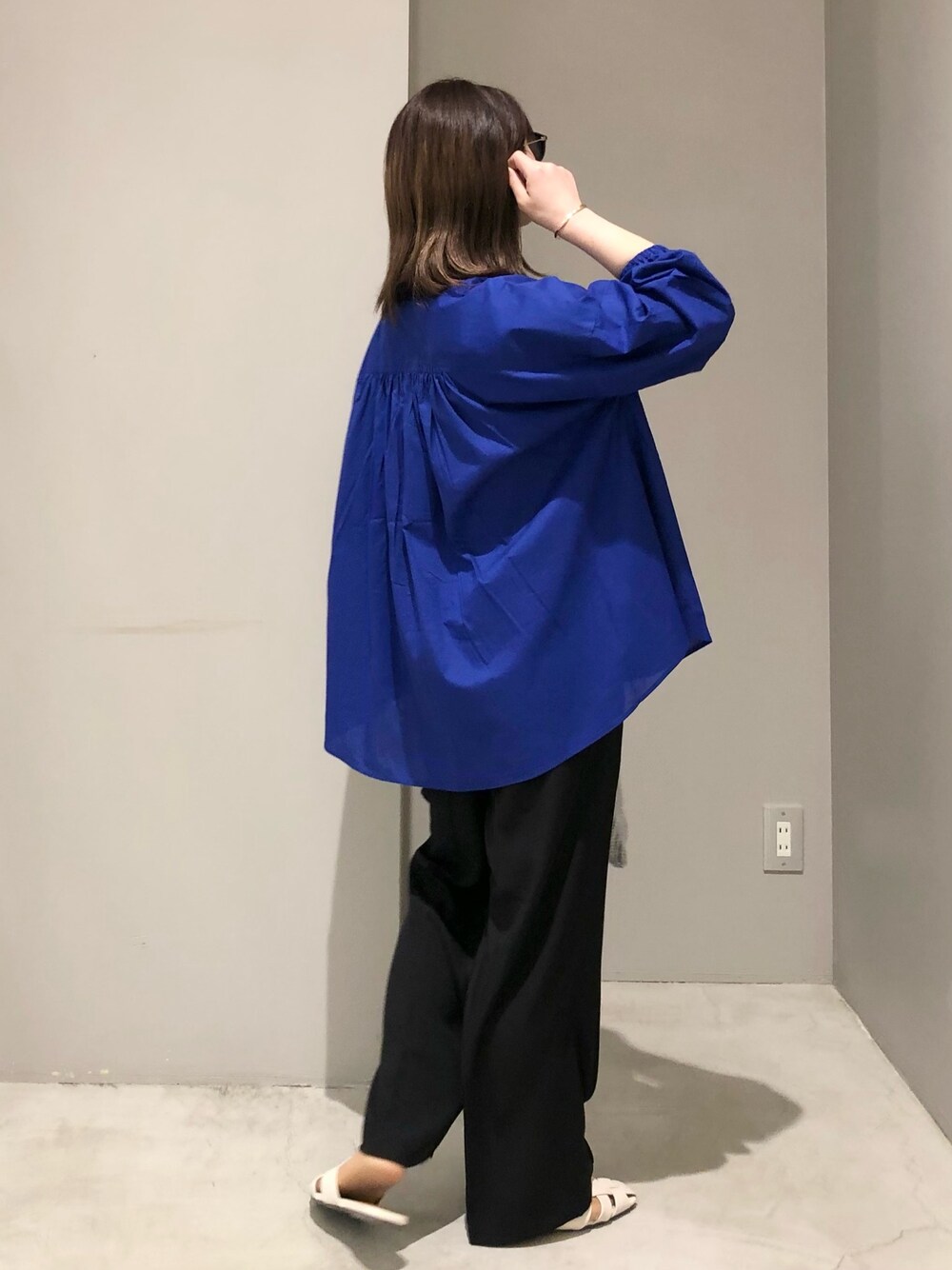 ホワイト系のサンダル、ブラック系のスラックス、シルバー系のハンドバッグを着用したレディースの春コーディネートの2枚目の写真