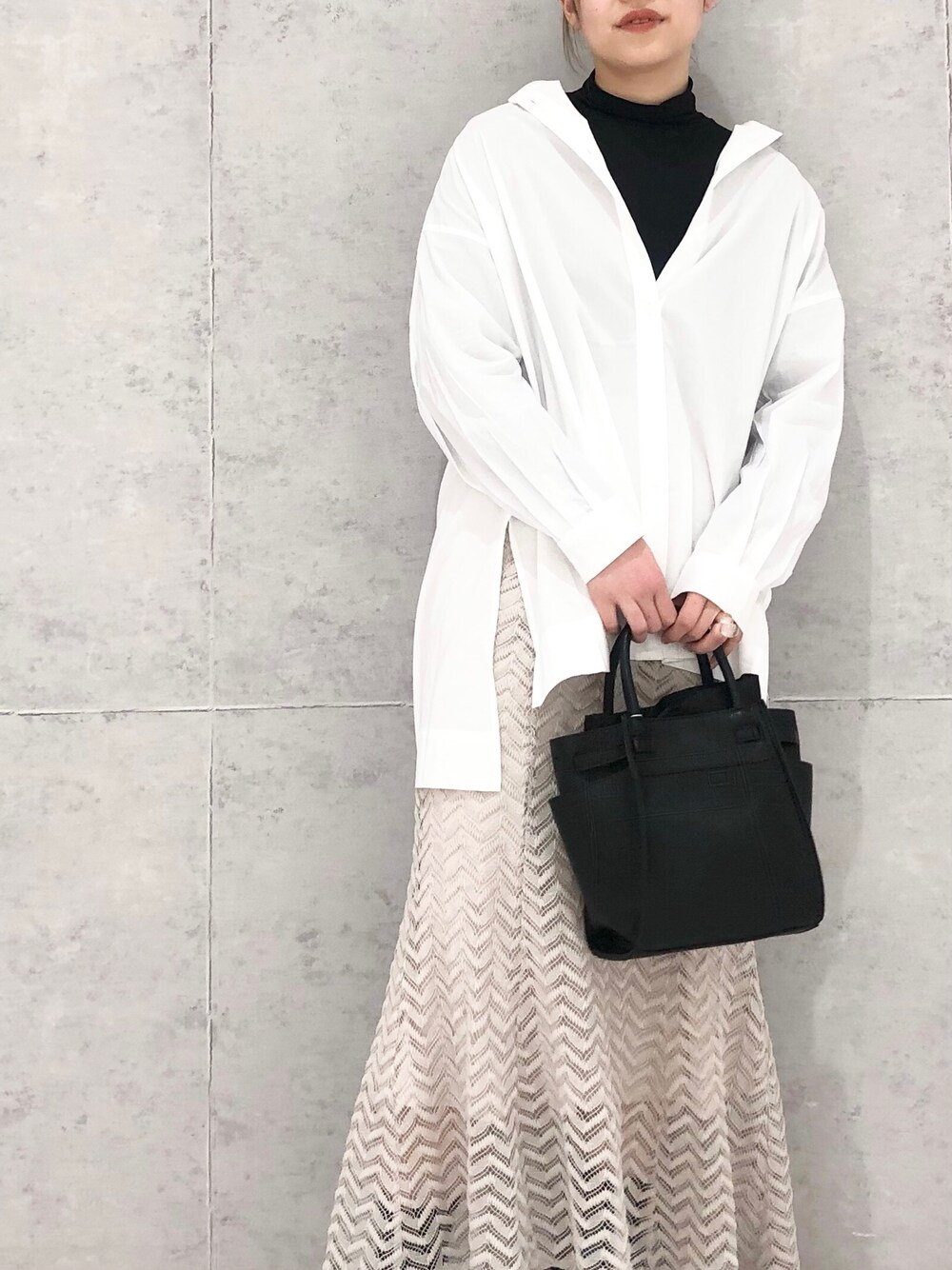 ベージュ系のスカート、ブラック系のショルダーバッグ、ブラック系のブーツを着用したレディースの冬コーディネートの3枚目の写真