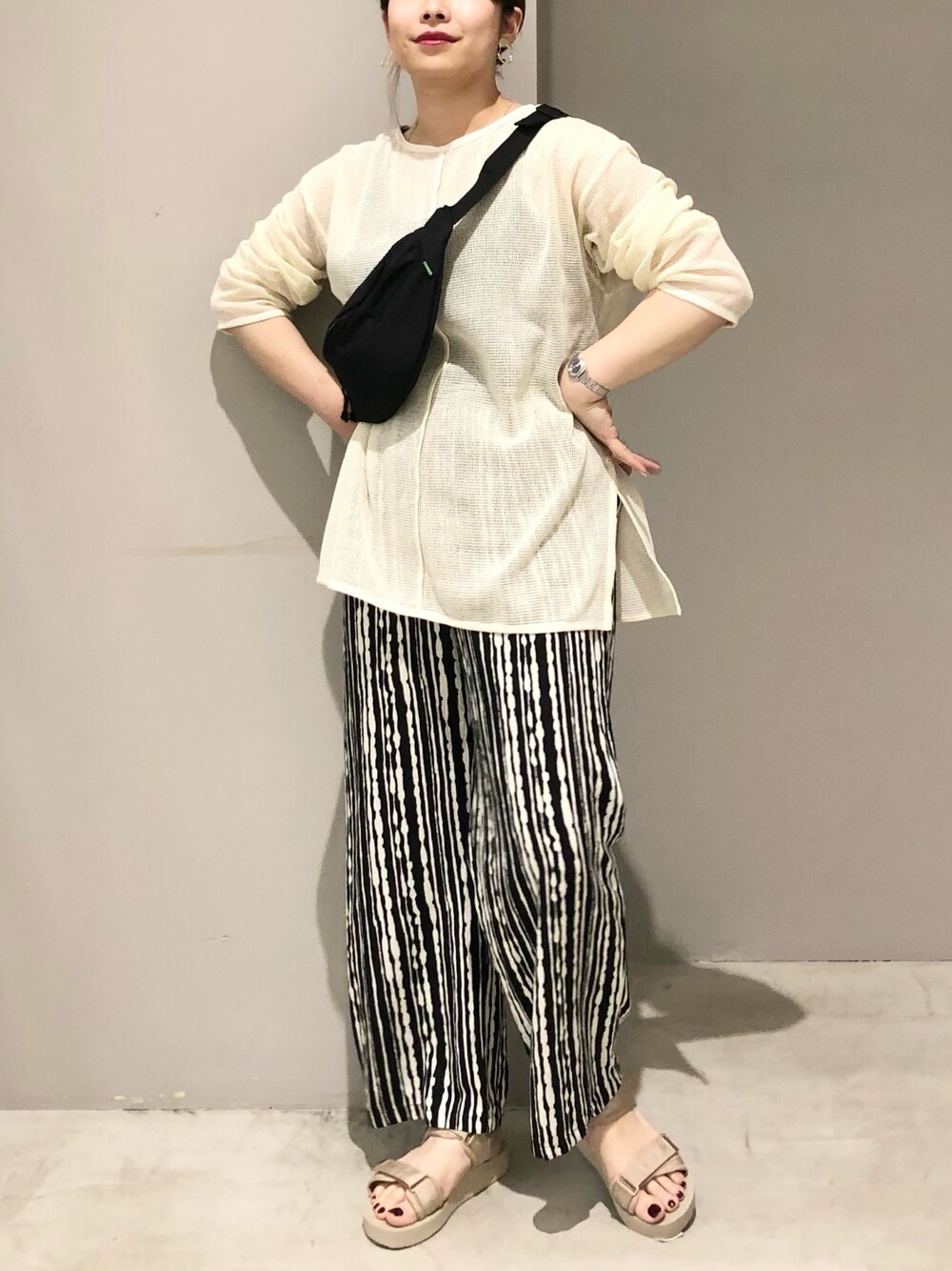 ホワイト系のニット/セーター、ブラック系のその他パンツ、ベージュ系のサンダルを着用したレディースの夏コーディネートの2枚目の写真